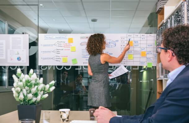 Female coach explaining project management studies over glass wall Female coach explaining project management studies over glass wall