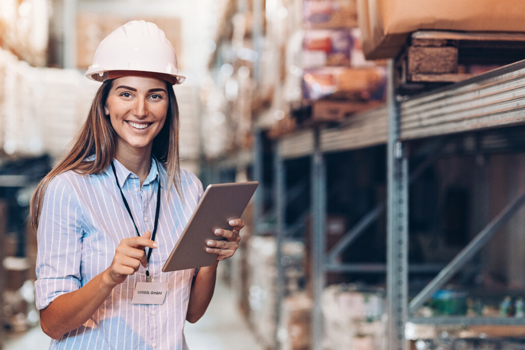 Cheerful woman working in a warehouse Smiling young woman with digital tablet in a warehouse