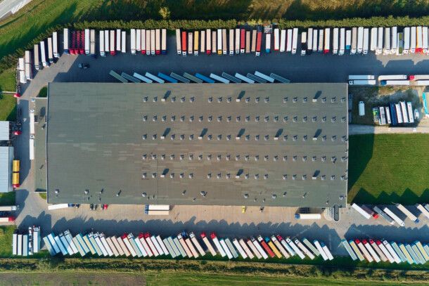 Parking lot for semi trucks near factory, top view. Aerial view of truck trailers parked for waiting loading on factory. Logistics and shipping