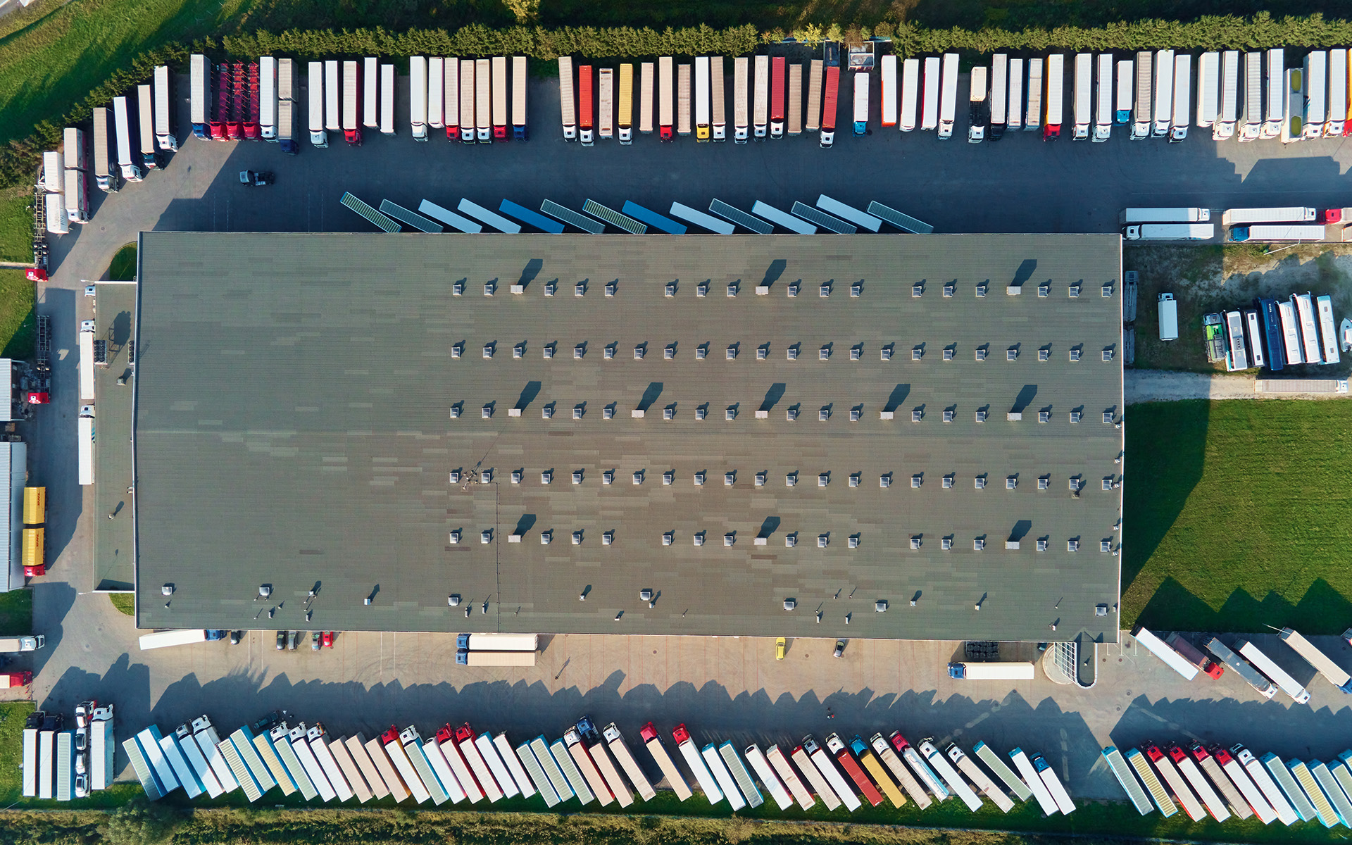 Factory warehouse with parked semi trucks, aerial view Parking lot for semi trucks near factory, top view. Aerial view of truck trailers parked for waiting loading on factory. Logistics and shipping