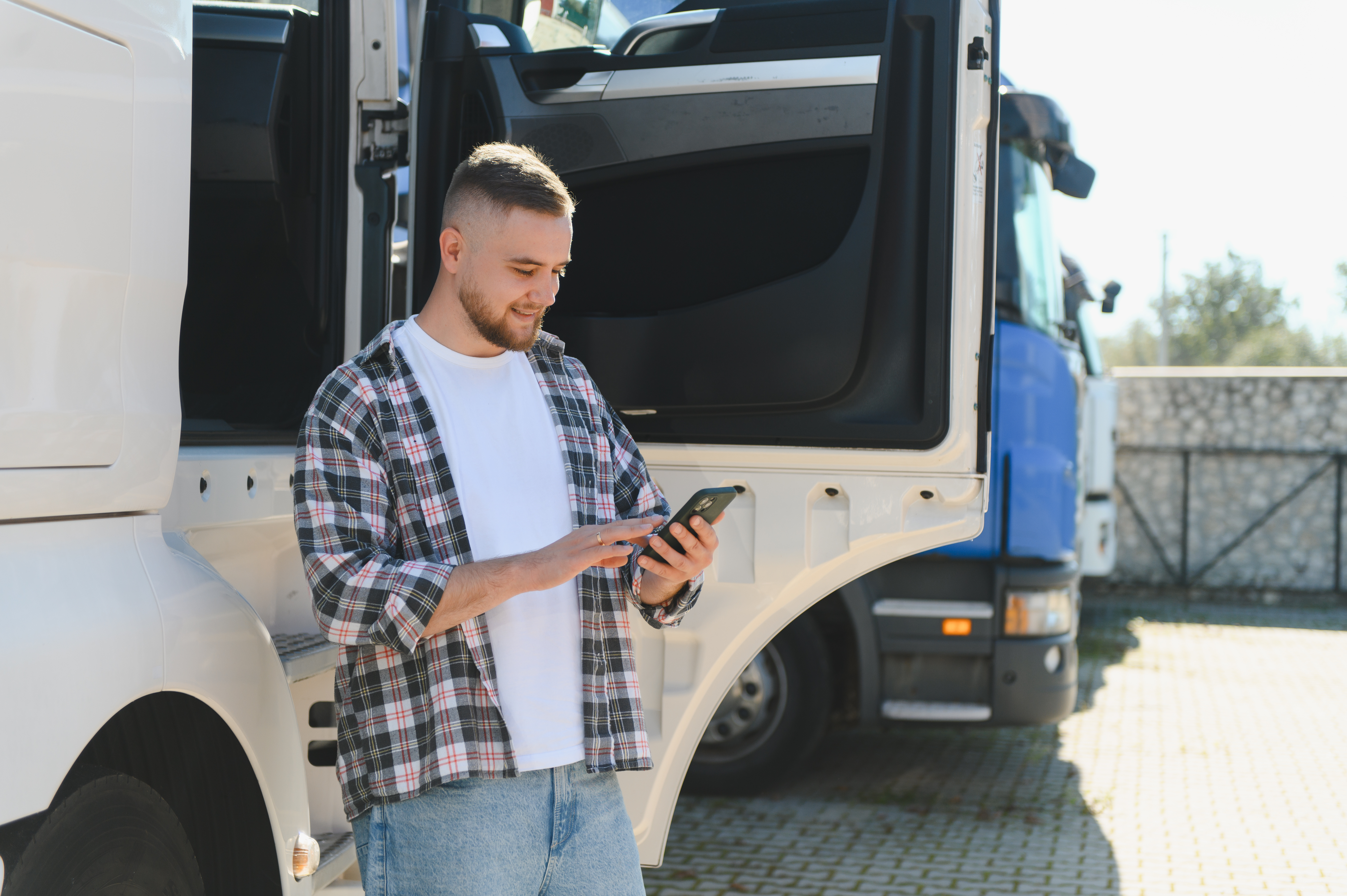 Young truck driver using smartphone at semi truck